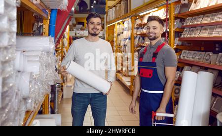 Glücklicher junger Mann, der in einem modernen Baumarkt für sein Haus Lüftungsrohre einkauft Stockfoto