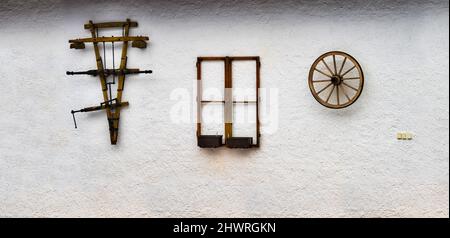 Drei alte hölzerne historische Artefakt, Teil der Tier Kragen zu Wagen oder Pflug, Fenster und Rad, hängen an der weißen Wand des Dorfes Bauernhaus, Tschechische r Stockfoto