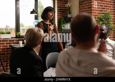 Beeindruckte Frau, die von einer Gruppe von Menschen beim Programm für ein Treffen Beifall erhielt. Die Patienten klatschen in die Hände und feiern Erfolge und unterstützen freudige Menschen. Stockfoto