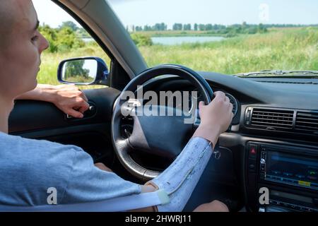 Prothetischer ampuierter Arm des kaukasischen Mannes am Lenkrad, der das Auto fährt Stockfoto