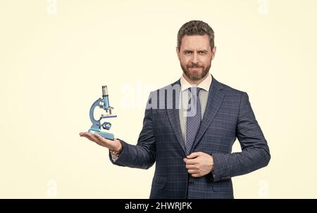 Unternehmer Mann in Geschäftsanzug präsentiert moderne Mikroskop isoliert auf weiß, Erfindung. Stockfoto