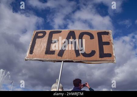 London, Großbritannien. 6.. März 2022. Ein Protestler hält am Trafalgar Square ein Friedensschild. Anti-Kriegs-Demonstranten marschierten durch Central London, um gegen den Krieg in der Ukraine, die Erweiterung der NATO und Atomwaffen zu protestieren. Stockfoto