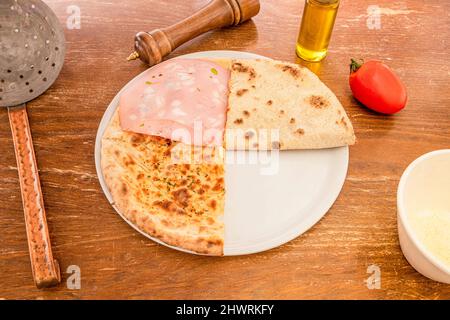 Knusprige Pizza mit bologna Mortadella, ohne Käse, mit Öl, Orangano und Pfeffer auf einem Holztisch Stockfoto