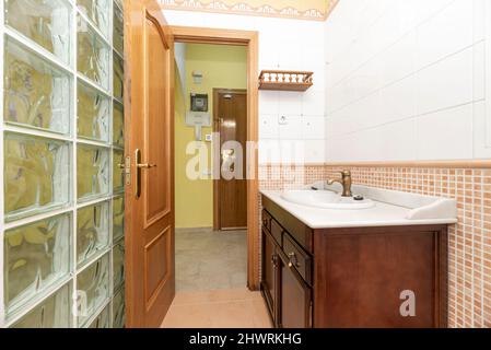 Schönes Badezimmer mit dunklen Holzmöbeln, weißer Marmorplatte, durchsichtiger Glaswand und dem anderen mit braunen Fliesen Stockfoto