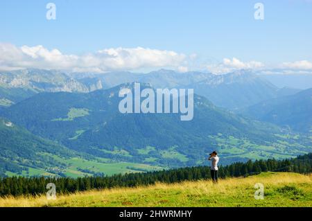 Junger, nicht erkennbarer Mann, der die idyllische Sommerlandschaft mit dem Mont Blanc in den Alpen fotografiert. Annecy Lake Area, Haute-Savoie, Frankreich. Stockfoto