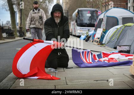 Ein Protestler sah, wie er Flaggen der Länder festsetzte, deren Volk unter autoritären Regimes im Lager schuften.das Freedom Convoy Camp wurde dauerhaft am Ufer errichtet, nachdem der Freedom Convoy im Februar 2022 nach London kam. Sie unterstützen die Menschen, die gegen autoritäre Regierungen kämpfen, die in Kanada, Österreich und Australien unter den beschwerlichen Coronavirus-Gesetzen leben. Sie kämpfen auch gegen die Impfung von Kindern im Vereinigten Königreich. Bis die Regierungen alle Freiheiten zurückgeben, die den Menschen in den letzten zwei Jahren genommen wurden, wollen sie bleiben. Stockfoto