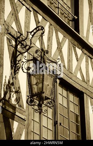 Antike Laterne, die auf einem Fachwerkhaus in der mittelalterlichen Stadt Auxerre, Burgund, Frankreich, hängt. Sepia historisches Foto. Stockfoto