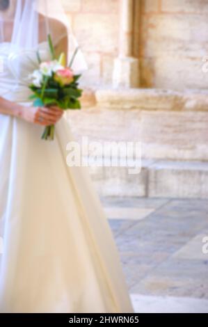 Verschwommenes Foto einer Braut, die an ihrem Hochzeitstag in die gotische Kirche eintrat. Stockfoto