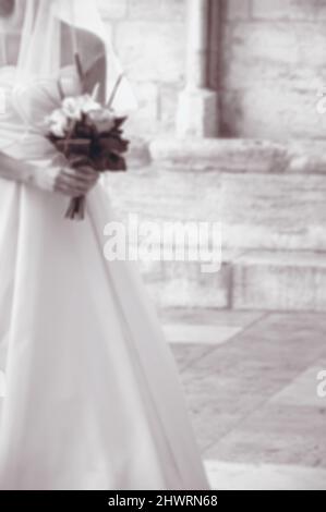 Verschwommenes Foto einer Braut, die an ihrem Hochzeitstag in die gotische Kirche eintrat. Sepia Retro historisches Foto Stockfoto