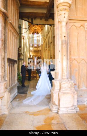 Verschwommenes Foto der Hochzeitszeremonie in der gotischen Kirche. Vater bringt Tochter zum Altar. Frankreich Stockfoto