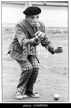 Ein sehr fetziger älterer Mann, wahrscheinlich ein italienischer Amerikaner, passt seinen nächsten Zug in einem Bocce-Spiel in Midtown Manhattan, New York City, auf. 1978. Stockfoto