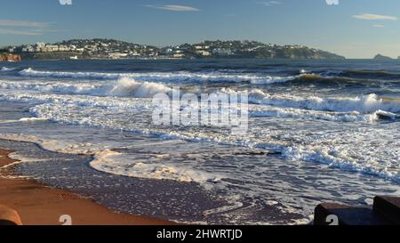 Schäumende Wellen am Strand von Preston in Paignton, South Devon, mit Blick auf Torquay. Stockfoto