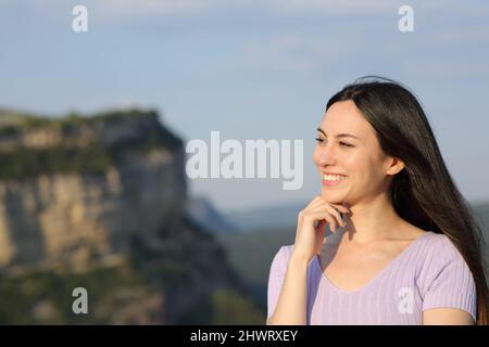 Nachdenkliche glückliche asiatische Frau, die in der Natur zur Seite steht Stockfoto