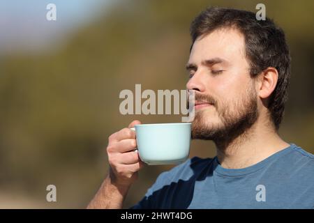 Entspannter Mann, der in der Natur eine Tasse Kaffee genießt Stockfoto