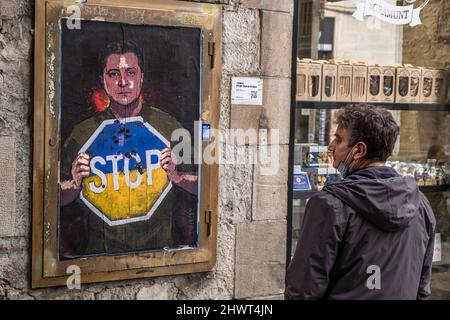 Barcelona, Spanien. 07. März 2022. Ein Passant sieht die grafische Darstellung des ukrainischen Präsidenten Zelensky, der ein Ende der russischen Invasion fordert, auf der Plaza de Sant Jaume.der in Barcelona lebende italienische Künstler TvBoy stellt eine Collage-Darstellung des ukrainischen Präsidenten Volodímir Zelensky auf, der nach dem Ende der russischen Invasion fragt Besetzung in einem der Zugänge zur Plaza Sant Jaume. Kredit: SOPA Images Limited/Alamy Live Nachrichten Stockfoto