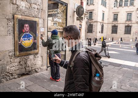 Barcelona, Spanien. 07. März 2022. Zwei Personen werden dabei gesehen, wie sie Fotos von der Collage machen, die den ukrainischen Präsidenten Zelensky zeigt, der ein Ende der russischen Invasion auf der Plaza de Sant Jaume fordert.der in Barcelona lebende italienische Künstler TvBoy stellt eine Collage-Darstellung des ukrainischen Präsidenten Volodímir Zelensky auf, der um das Ende des russischen Präsidenten bittet Besetzung in einem der Zugänge zur Plaza Sant Jaume. Kredit: SOPA Images Limited/Alamy Live Nachrichten Stockfoto