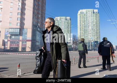 Kiew, Ukraine. 26.. Februar 2022. Ein Anwohner trägt Nachschub, um als Mitglieder des Kiewer Verteidigungs-Bataillons auf der Straße nach möglichen russischen Angriffen in sein Haus zurückzukehren. Kredit: SOPA Images Limited/Alamy Live Nachrichten Stockfoto