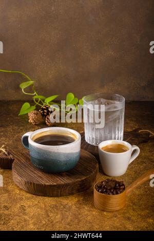 Ein aromatischer Kaffee, der frisch zum Ausgießen gemahlen wird, wird auf einem rustikalen Holztablett zu heißem oder kaltem schwarzen Kaffee Stockfoto