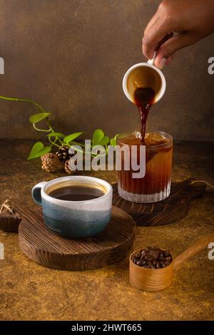 Ein aromatischer Kaffee, der frisch zum Ausgießen gemahlen wird, wird auf einem rustikalen Holztablett zu heißem oder kaltem schwarzen Kaffee Stockfoto
