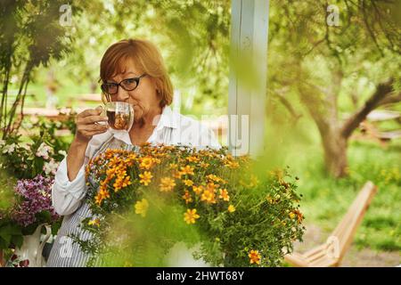 Elegante reife Dame trinkt Tee auf dem Land Stockfoto