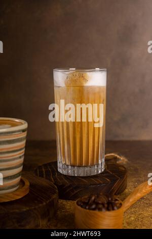 Ein aromatischer Kaffee, der frisch zum Ausgießen gemahlen wird, wird auf einem rustikalen Holztablett zu heißem oder kaltem schwarzen Kaffee Stockfoto