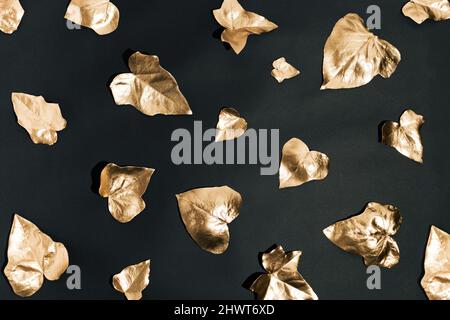 Kreatives Naturlayout. Goldene Efeu-Blätter auf schwarzem Hintergrund. Minimale abstrakte goldene Komposition. Stockfoto