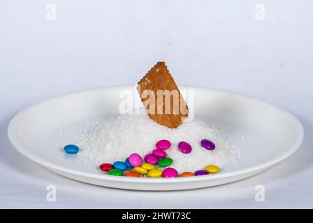 Biscuit In Heap Of Sugar In White Plate Mit Schokoladensteinen, Isoliert Auf Weißem Hintergrund Stockfoto