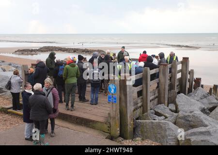 Gruppe von Einheimischen und Besuchern auf einer geführten Tour durch den Strand von Bulverhythe, die das Schiffswrack von Amsterdam und den alten Wald, Hastings, East Sussex, Großbritannien, erkundet Stockfoto