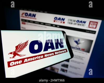 Smartphone mit Logo des amerikanischen Medienunternehmens One America News Network (OANN) auf dem Bildschirm vor der Website. Konzentrieren Sie sich auf die Mitte des Telefondisplays. Stockfoto