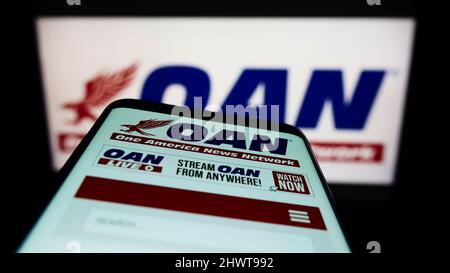 Mobiltelefon mit Webseite des US-Medienunternehmens One America News Network (OANN) auf dem Bildschirm vor dem Logo. Konzentrieren Sie sich auf die obere linke Seite des Telefondisplays. Stockfoto