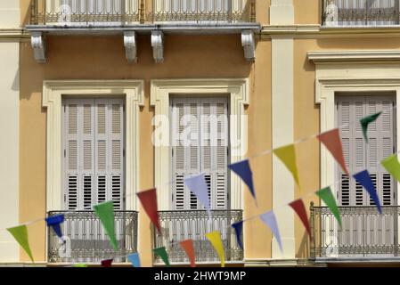 Alte historische neoklassizistische Gebäudefassade mit passenden Balkonen, grauen Holzfensterläden und ionischen Säulen an einer ockerfarbenen Stuckwand in Nafplio Griechenland. Stockfoto