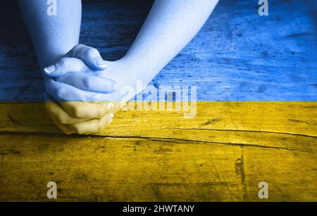 Eine ukrainische Flagge auf betenden Händen Stockfoto