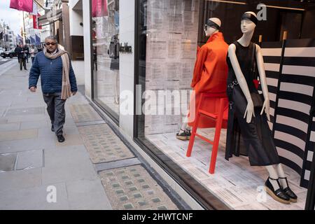 Mann, der am 3.. März 2022 in London, Großbritannien, an den Schaufensterpuppen von Max Mara in der Bond Street vorbeikam. Die Bond Street ist eine der Hauptstraßen im Einkaufsviertel West End und sehr nobly. Seit dem 18.. Jahrhundert ist es eine modische Einkaufsstraße. Die reichen und wohlhabenden Shop hier vor allem für High-End-Mode und Schmuck. Stockfoto