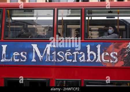 Die Londoner sitzen auf dem Oberdeck eines Busses, der ironischerweise mit einer Anzeige für Les Miserables während des zweiten U-Bahnstreiks in einer Woche prangt, der am 3.. März 2022 alle U-Bahnlinien in London, Großbritannien, ausgesetzt hat. In einem bei der Öffentlichkeit sehr unbeliebten Schritt gingen Mitglieder der RMT-Gewerkschaft weitere 24 Stunden in einem festgefahrenen Streit um Arbeitsplätze, Renten und Arbeitsbedingungen aus, was einigen den täglichen Pendelweg sehr schwer gemacht hat. Stockfoto