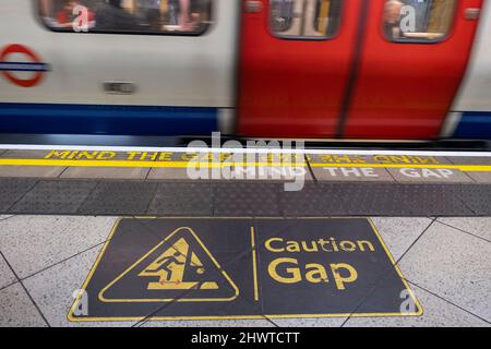 Beachten Sie das Warnschild der Gap-U-Bahn-Plattform auf einem Bahnsteig der Londoner U-Bahn am 5.. März 2022 in London, Großbritannien. Beachten Sie, dass es sich bei der Lücke um eine akustische oder optische Warnphrase handelt, die den Bahnreisenden zur Vorsicht beim Überqueren des horizontalen und in einigen Fällen vertikalen Spaltabstands zwischen dem Bahnhofseingang und dem Bahnsteig ausgegeben wird. Stockfoto