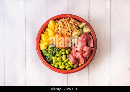 Große Schüssel mit gehacktem roten Thunfisch mit Mango, Massogerogen, Edamame-Bohnen, Wakame-Algen, Avocado, Weißer Reis und knusprige Zwiebel Stockfoto