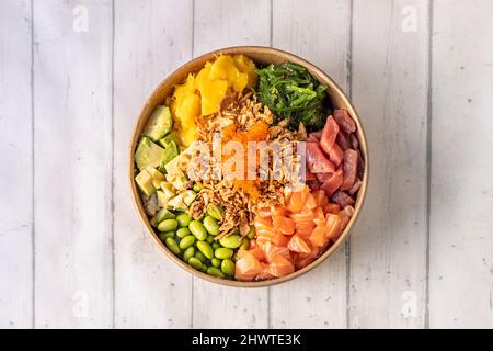 Gemischter norwegischer Lachs- und Blauflossen-Thunfisch-Poke-Schüssel mit knuspriger Zwiebel, Tobiko Masago Roe, reifer Mango, gewürfelter mexikanischer Avocado, weißer Reis, Wakame-Algen Stockfoto