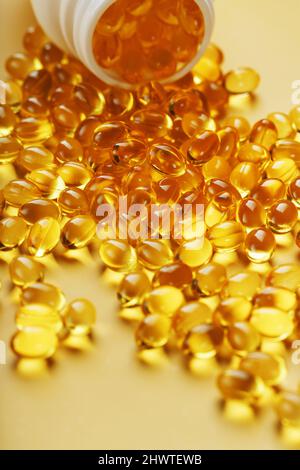 Gold Vitamin D3 Kapseln aus einem Glas auf einem gelben Hintergrund mit freiem Platz gegossen. Das wichtigste Vitamin in einer leicht verdaulichen flüssigen Form. Stockfoto