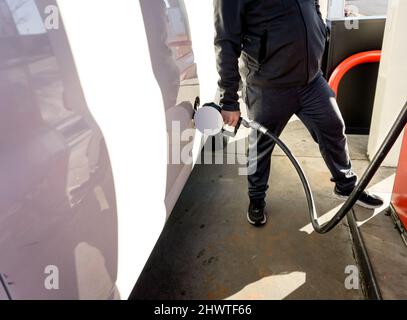 Ein Mann füllt seinen Van mit teurem Benzin. Stockfoto