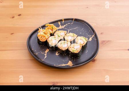 Dickes Maki-Gericht, gefüllt mit Avocado, rotem Reis und Surimi auf einem Kiefernholztisch Stockfoto