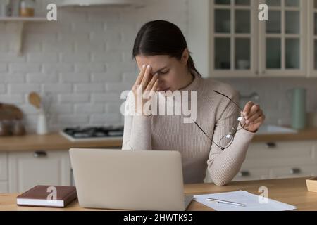 Müde Frau zieht aus Brille Rest von der Arbeit auf Laptop Stockfoto