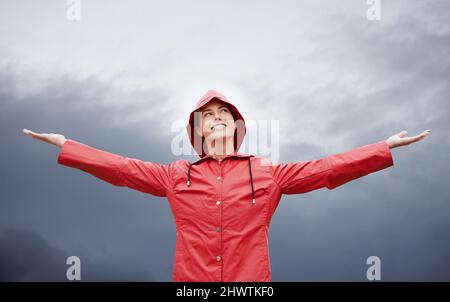 Ich bin auf alles vorbereitet. Kurzer Schuss einer attraktiven jungen Frau, die im Regen steht. Stockfoto