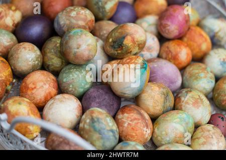 Bunte Ostereier in Pastelltönen in großen Mengen in weißem Korb gehäuft Stockfoto