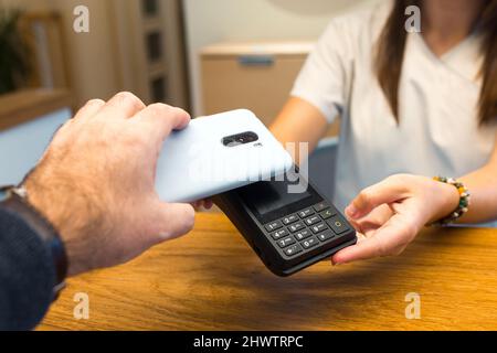 Mann mit Smartphone für die Zahlung über Terminal Stockfoto