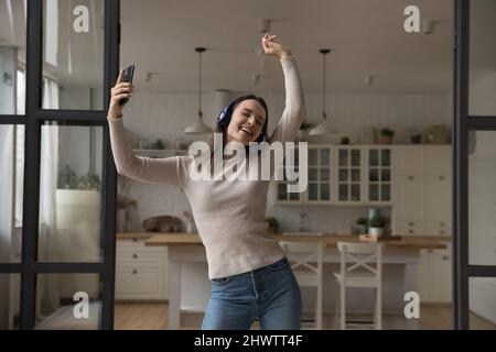 Frau hält Smartphone, hören Musik über Kopfhörer zu Hause Stockfoto