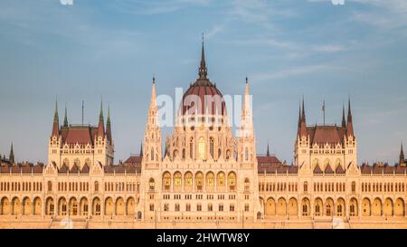 Das ungarische Parlamentsgebäude, ein bemerkenswertes Wahrzeichen Ungarns in Budapest. Blick auf die Hauptfassade im Sonnenuntergang. Stockfoto