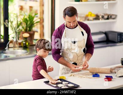 Weil Cookies die Welt zu einem besseren Ort machen. Aufnahme eines Vaters und eines Sohnes, der in der Küche Kekse backt. Stockfoto