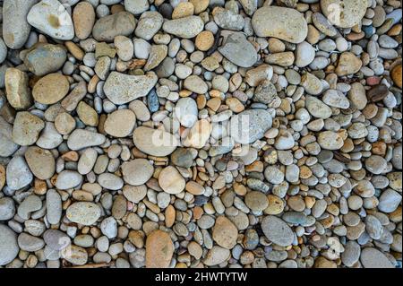 Glatte Meereskiesel, Blick von oben. Musterung der Meeresschlacke. Mauerwerk-Glätte am Meeresstrand mit natürlichem Licht. Muster mariner Kies. Stein strukturiert auf se Stockfoto