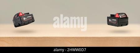 Akku für Akku-Bohrmaschine. Schrauberbatterie. Vier Batterien mit Ladeanzeige liegen auf einem Holzhintergrund Stockfoto