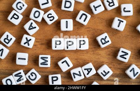 Kleine weiße und schwarze Perlenwürfel auf Holzbrett, Buchstaben in der Mitte buchstabieren PPP - Lob, Bild, Push-Konzept Stockfoto